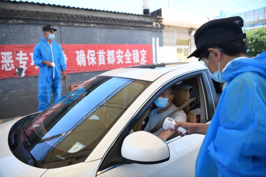 Un personal de seguridad con un traje de protección verifica la temperatura de las personas que ingresan al mercado de Xinfadi en Beijing el 14 de junio de 2020. Un personal de seguridad con un traje de protección verifica la temperatura de las personas que ingresan al mercado de Xinfadi en Beijing el 14 de junio de 2020.