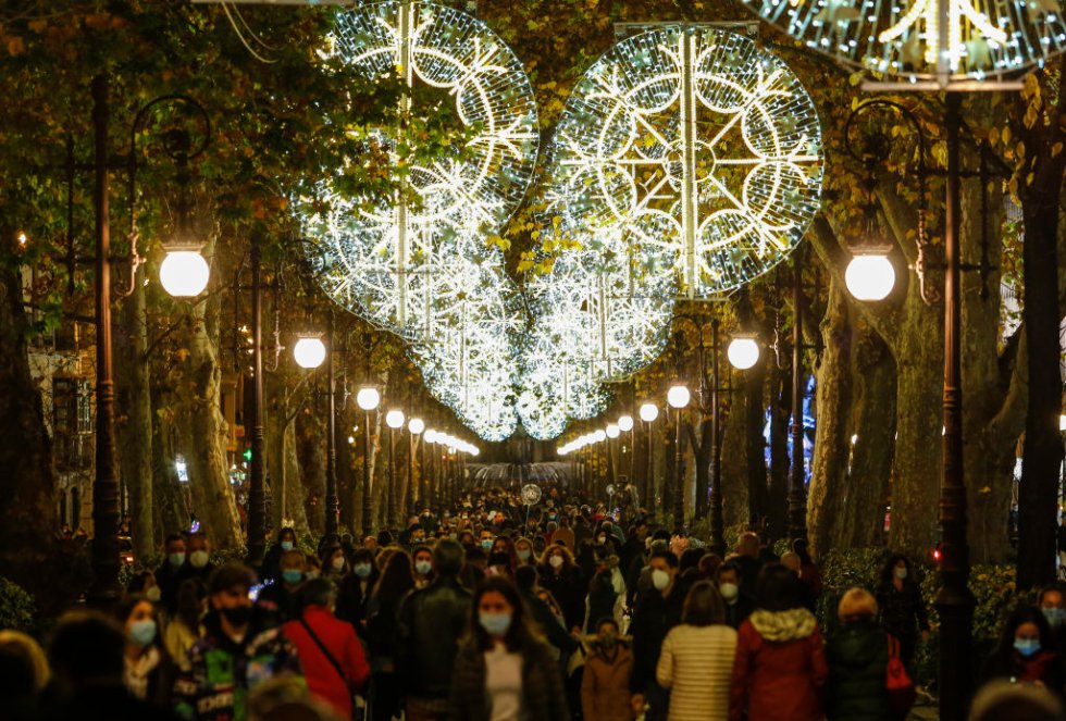 Mucha gente caminando en una calle decorada con luces navideñas en medio de la pandemia en Granada, España